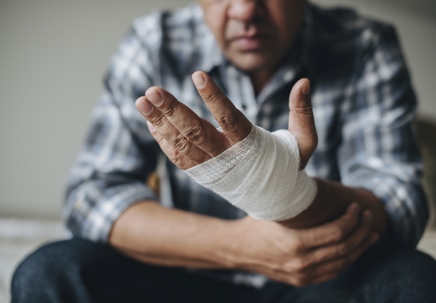A man holding his bandaged hand, indicating injury or pain. | Raiser, Kenniff & Lonstein